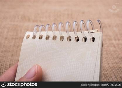 brown color spiral notebook in hand on a canvas background