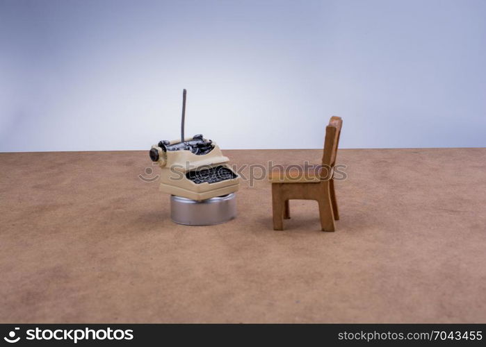 Brown color wooden toy chair and a type writer on brown background