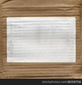 Brown corrugated cardboard background. Brown corrugated cardboard texture useful as a background with blank white label on a box with copy space