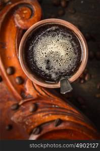 Brown cup of coffee on rustic wooden background, top view, close up