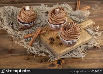 brown cupcakes with cocoa cream, cinnamon and coffee. brown cupcakes with cocoa cream, cinnamon and coffee on wooden background