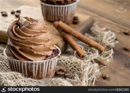 brown cupcakes with cocoa cream, cinnamon and coffee. brown cupcakes with cocoa cream, cinnamon and coffee on wooden background