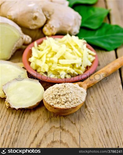 Brown dish with grated ginger, a wooden spoon with powder, ginger root, green leaves on wooden board