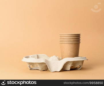 brown disposable cups in paper holder on blue background, rejection of plastic, zero waste
