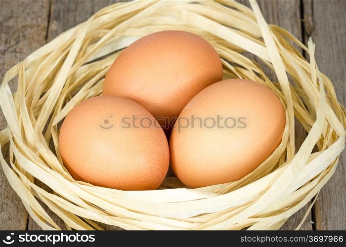 Brown eggs in the nest on the wooden floor