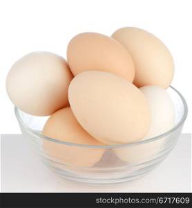 Brown eggs in transparent bowl on white background.
