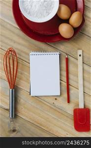 brown eggs with flour plate≠ar sπral notepad whisk pencil spatula wooden surface