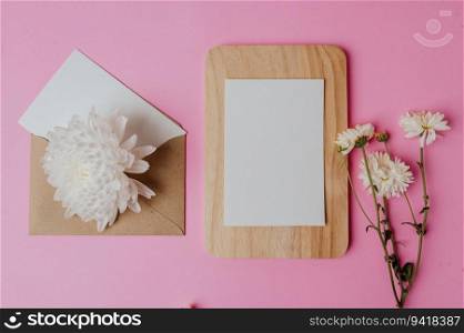 brown envelope, flower and blank card on wood plate with pink background