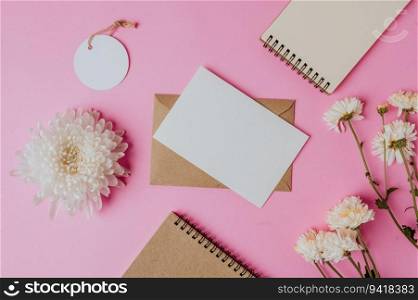 brown envelope, tag, notebook with blank card and flower on pink background