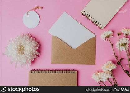 brown envelope, tag, notebook with blank card and flower on pink background