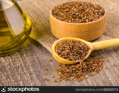 Brown flax seeds and flaxseed oil on a wooden table