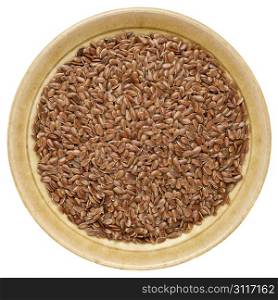 brown flax seeds in a round ceramic bowl isolated on white