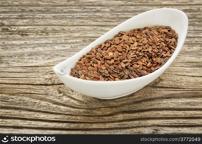 brown flax seeds in a small ceramic bowl against grained wood