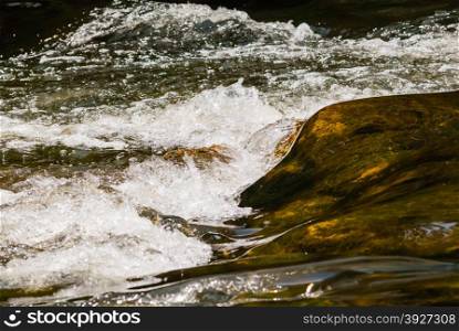 Brown flowing and white splashing river water.
