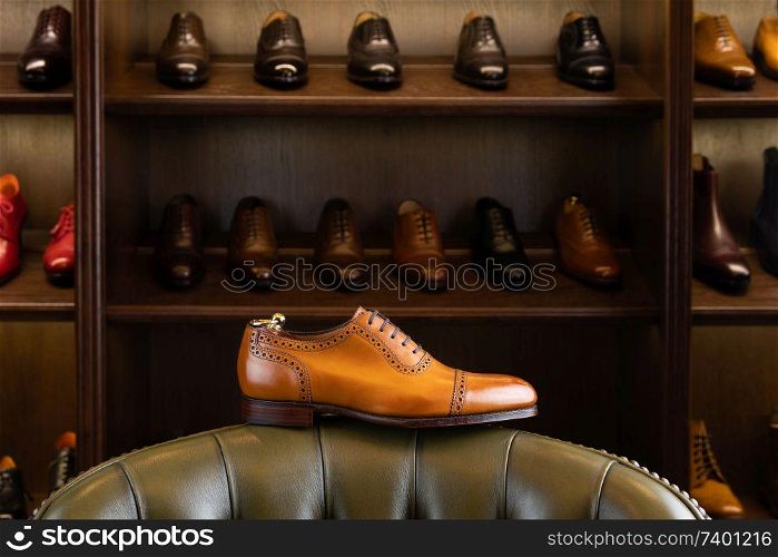 Brown full grain leather shoe in front of wooden display in men shoes boutique store.. men footwear boutique store