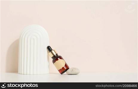 brown glass bottle with a pipette and a brown label stands on a stone. Container for cosmetics, serum and oil. Mockup skincare product