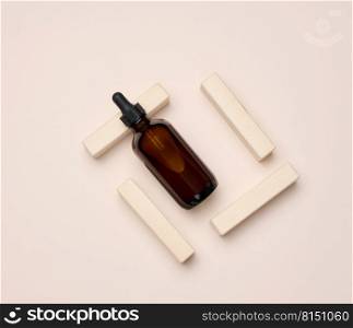 Brown glass bottle with a pipette on a beige background. Containers for cosmetics, oils, serum, top view