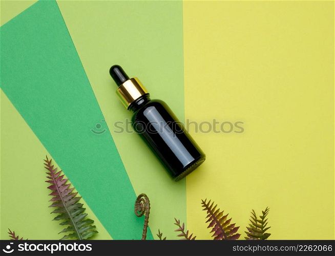 brown glass bottle with a pipette on a green background. Template for cosmetic liquid products, advertising and promotion