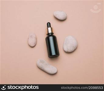 brown glass bottle with a pipette stands on a brown background. Container for cosmetics, serum and oil, flat lay