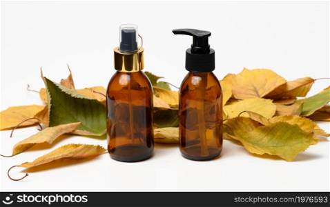 Brown glass bottle with black pump of cosmetic products on white table. Natural organic spa cosmetic, beauty concept. Mockup