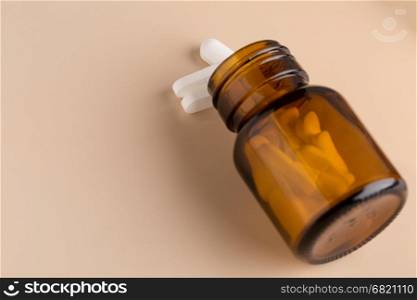 Brown glass pill bottle and white pills. Brown glass pill bottle and white pills on beige background