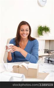 Brown hair female architect sitting at office holding cup of coffee