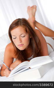 Brown hair woman lying on white sofa writing notes