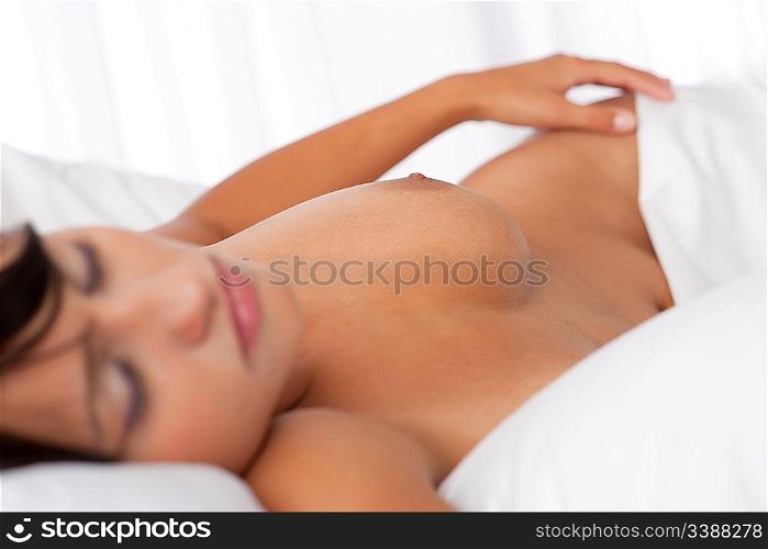 Brown hair woman sleeping naked in white bed, focus on nipple, shallow DOF