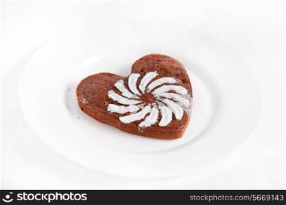 Brown heart shaped cookie with sugar powder on white plate&#xA;
