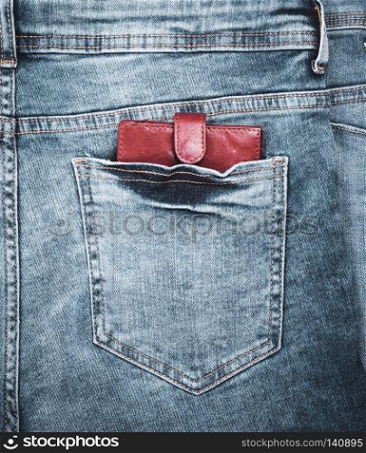 brown leather purse lies in the back pocket of blue jeans, close up, full frame