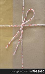 Brown mail package parcel wrap delivery tied up with string and adhesive tape on white background
