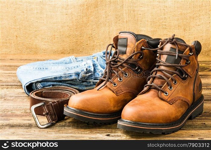 brown men&rsquo;s boots, jeans and belt on wooden background