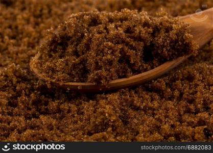 brown muscovado sugar in wooden spoon on the sugar background