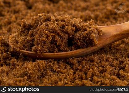 brown muscovado sugar in wooden spoon on the sugar background