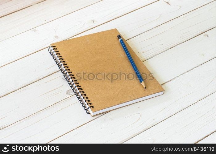 Brown notebook with blank pages and pencil on wood table