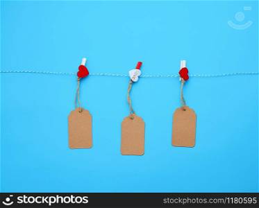 brown paper tag hanging on a rope and attached with a decorative clothespin, blue background