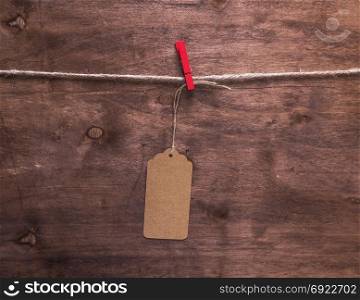 brown paper tag hanging on a rope, brown wooden background