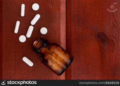 Brown pills bottles and heap of white pills. Brown pills bottles and heap of white pills on wooden table