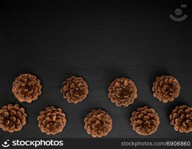 brown pine cones on a black wooden background, empty space above