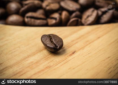 Brown roasted coffee beans on wooden board background.