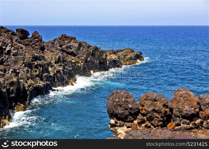 brown rock in white coast lanzarote spain beach stone water and summer