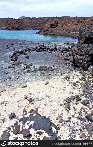brown rock in white coast lanzarote spain beach stone water and summer hervideros