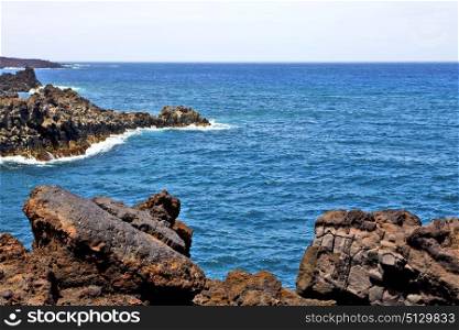 brown rock in white coast lanzarote spain beach stone water and summer hervideros