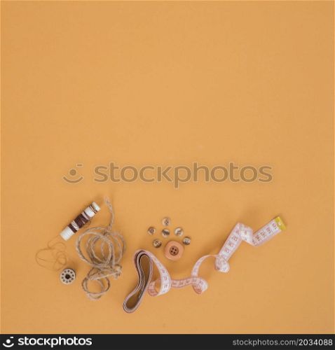 brown spool string buttons measuring tape orange backdrop