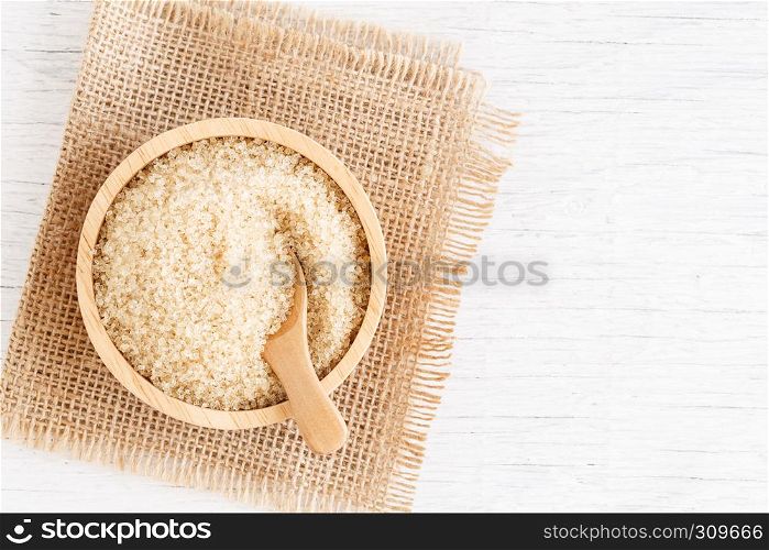 brown sugar and wood spoon in brown bowl on white wooden table, top view and copy space