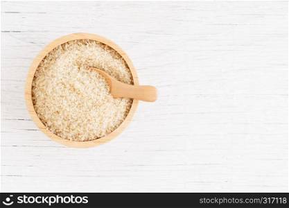 brown sugar and wood spoon in brown bowl on white wooden table, top view and copy space