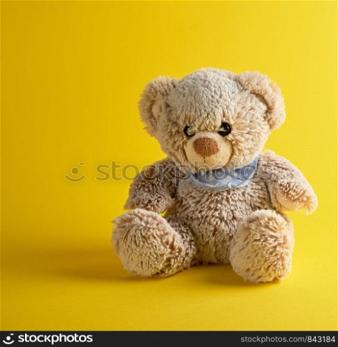 brown teddy bear sitting on a yellow background, tcopy space
