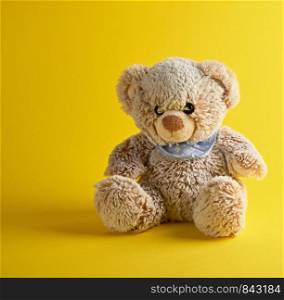 brown teddy bear sitting on a yellow background, tcopy space