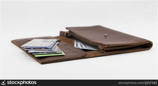 Brown wallet with credit cards and hundred dollar bills on white background. Credit cards in wallet