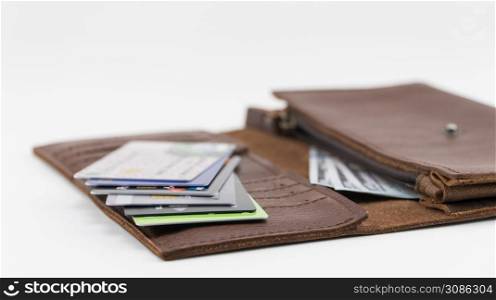 Brown wallet with credit cards and hundred dollar bills on white background. Credit cards in wallet